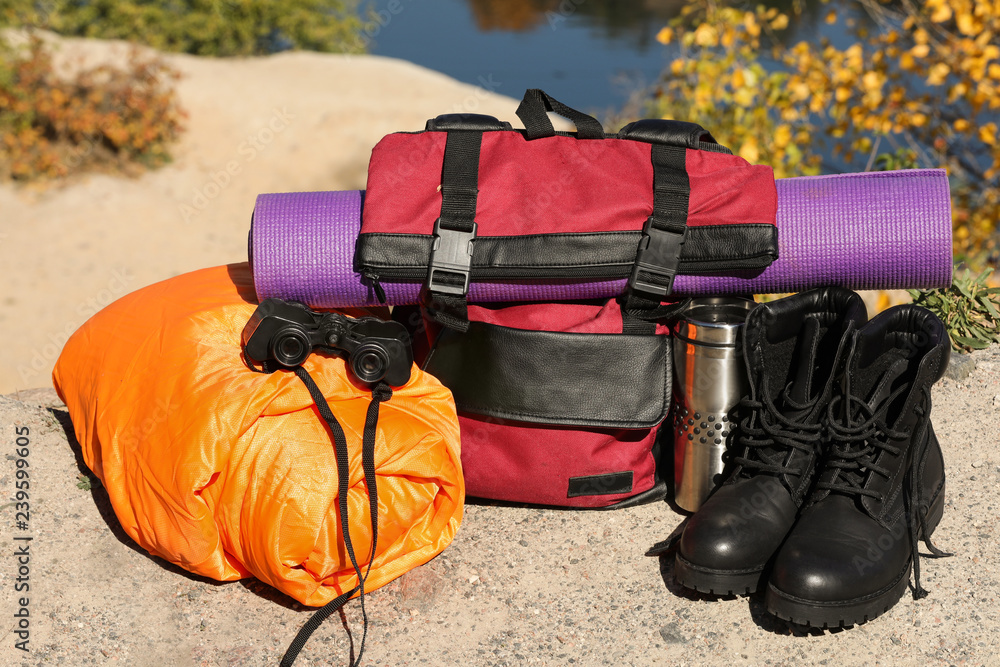 Set of camping equipment with sleeping bag on ground outdoors Set of camping equipment with sleeping bag on ground outdoors
