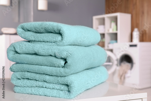 Stack of clean towels on table in laundry room. Space for text