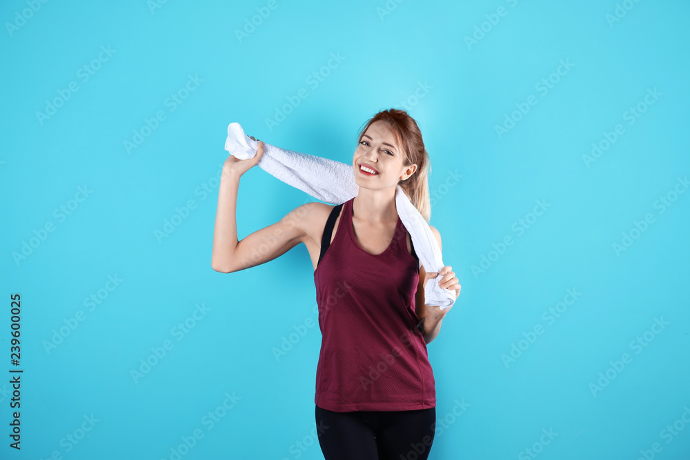 Beautiful young woman in sportswear with towel on color background Beautiful young woman in sportswear with towel on color background