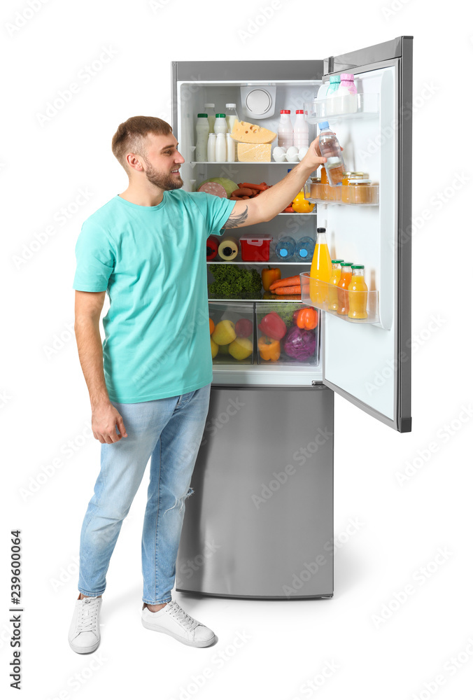 Young man taking bottle of water from refrigerator on white background Young man taking bottle of water from refrigerator on white background