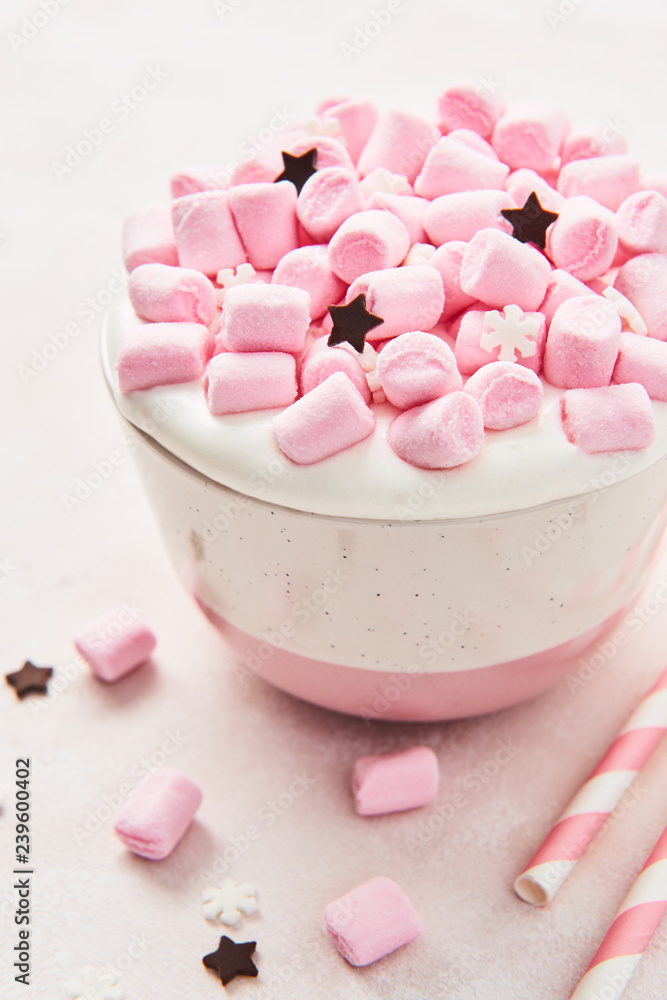 Hot chocolate or cocoa with whipped cream and pink marshmallow candy in pink and white mug with pink striped straws on abstract pink background. Top view. close up. Hot chocolate or cocoa with whipped cream and pink marshmallow candy in pink and white mug with pink striped straws on abstract pink background. Top view. close up.