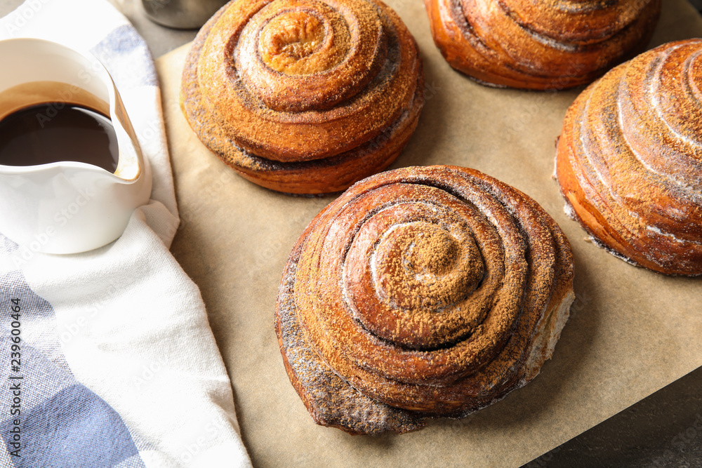 Fototapeta premium Cinnamon rolls and jug with chocolate syrup on table