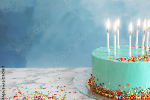 Fresh delicious birthday cake with candles on table against color background. Space for text