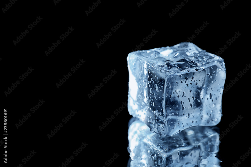 Ice cube on black mirror surface. Space for text Ice cube on black mirror surface. Space for text