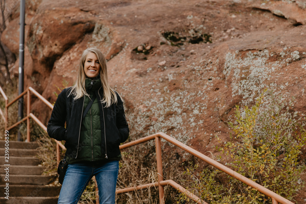Young Beautiful Modern Caucasian Woman Smiling While Traveling to Red Rocks Park in United States Outside in Nature at the State Park with Ancient Stone and Blue Sky Background