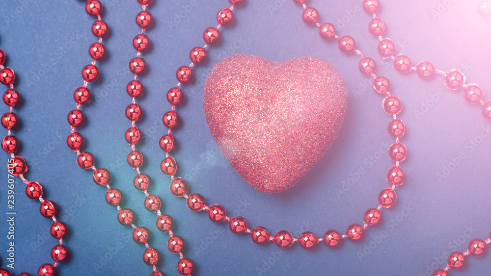 Obraz premium red heart on a blue paper background with red beads and flare flare. The concept of the day of lovers, Valentine's Day Copy Space