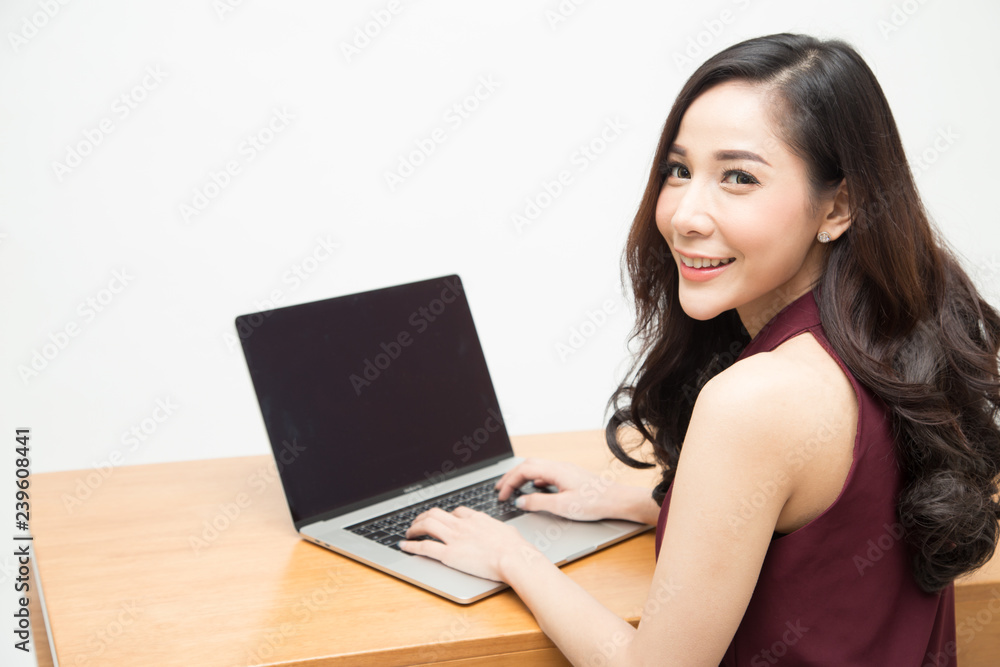 Young Asian woman in red work clothes smiling and working with laptop on the wood table, Women sitting at desk and working at computer notebook, Confident businesswoman concept Young Asian woman in red work clothes smiling and working with laptop on the wood table, Women sitting at desk and working at computer notebook, Confident businesswoman concept