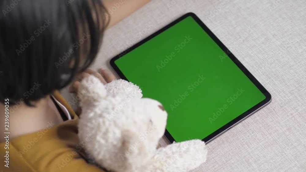 Asian girl using tablet with blank green screen on sofa Asian girl using tablet with blank green screen on sofa