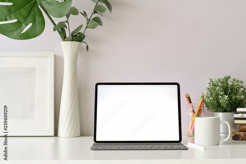 Front view workspace with blank screen modern tablet and home office supplies Front view workspace with blank screen modern tablet and home office supplies