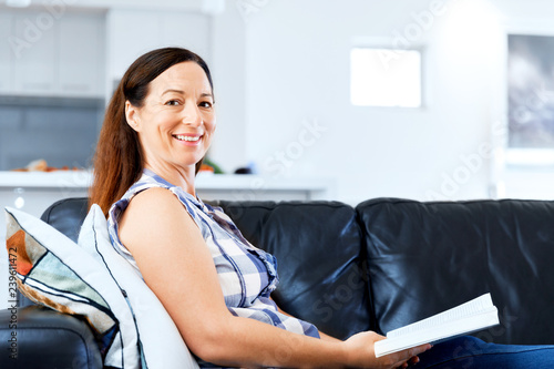 Happy woman reading a book relaxing on a sofa