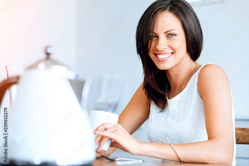 Obraz premium Happy young woman with cup of tea or coffee at home