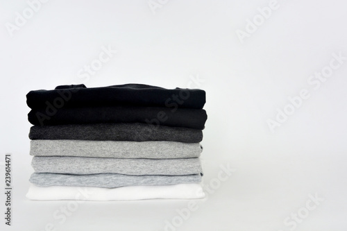 stack of folded black, grey and white color (monochrome) t-shirt on white background, copy space