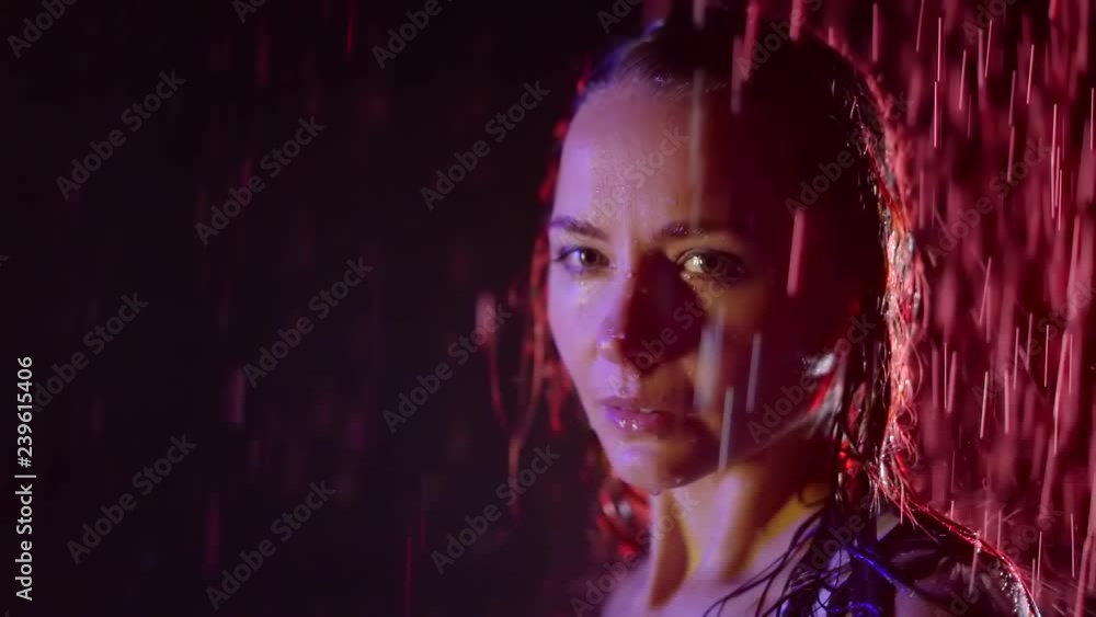 Beautiful indoor shooting of a sexy girl under rain in dark studio, pink light falling on her back, wet hot girl. Beautiful indoor shooting of a sexy girl under rain in dark studio, pink light falling on her back, wet hot girl.