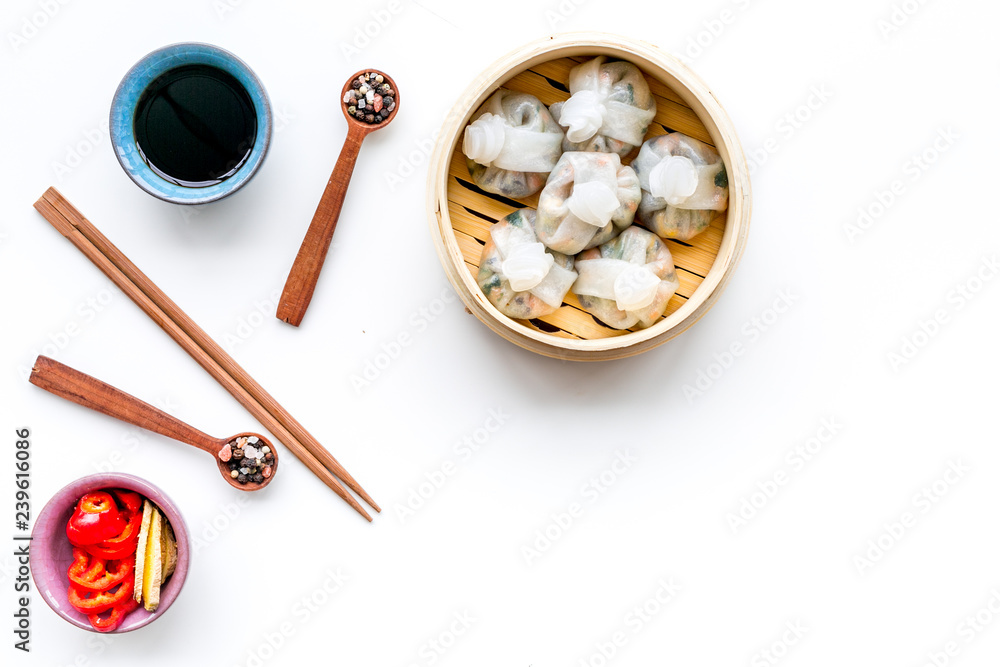Dinner in Chinese restaurant with dim sum, sticks and tea on white background top view space for text Dinner in Chinese restaurant with dim sum, sticks and tea on white background top view space for text
