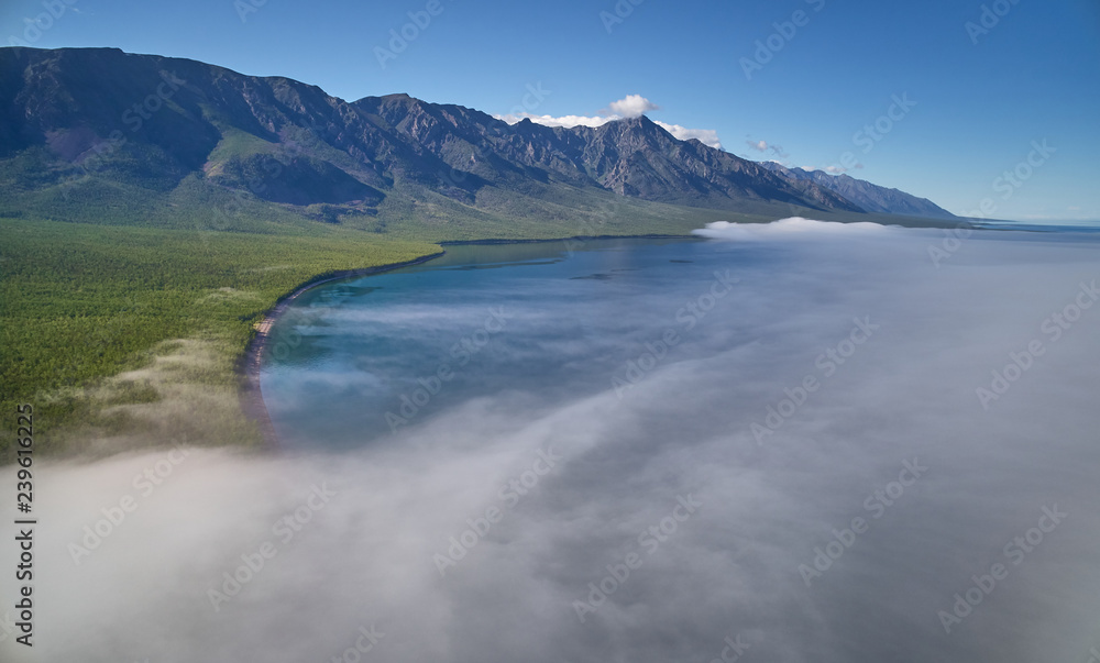 Obraz premium Mountain lake scenery with sun shining to the rocky morning mist above the lake