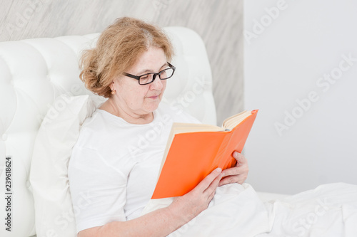 Senior woman with book on the bed