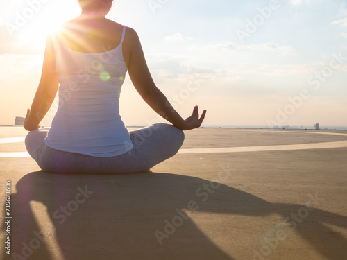 close up of back view of young woman hand meditation lotus pose on the rooftop building in the evening sky scene with city background