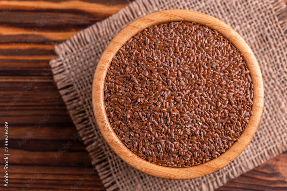 Raw flax seeds in wooden bowl with burlap napkin Raw flax seeds in wooden bowl with burlap napkin