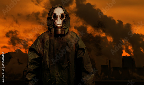 Man in gas mask and cloak of chemical protection with heavy industry plants