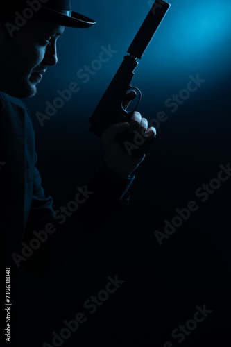 Portrait of side of man in black hat with pistol