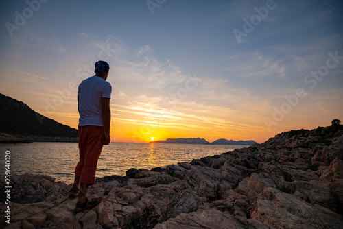 Traveler stands on the rock seashore