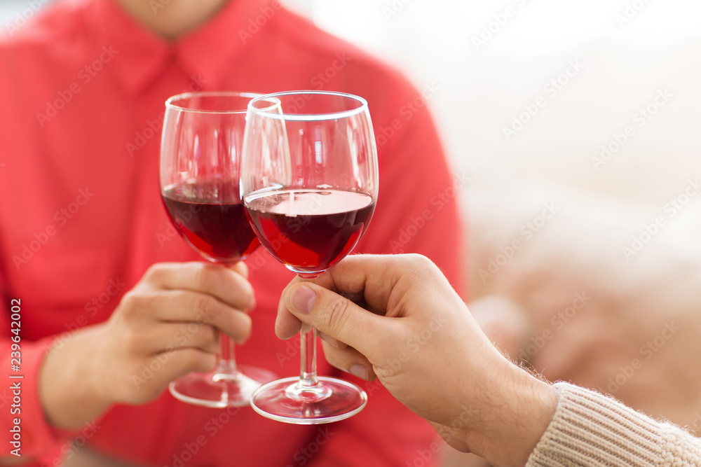 celebration, drinks and alcohol concept - hands of couple clinking red wine glasses