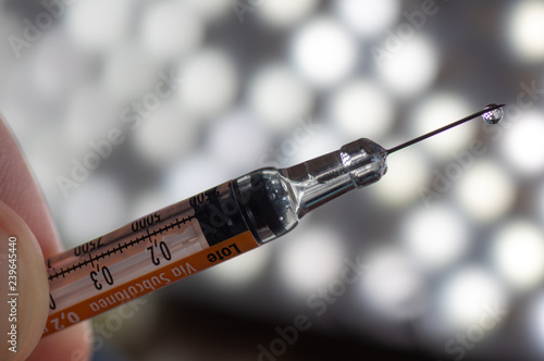 Heparin syringe with a drop on the tip of the needle on a background illuminated by LEDs