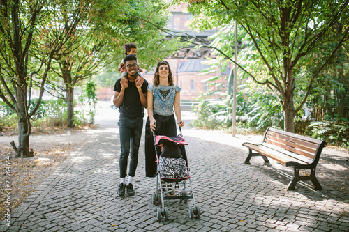 Family with stroller walking in park photo