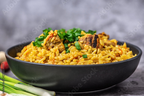 Rice pilaf with meat carrot and onion on grey background. Side view