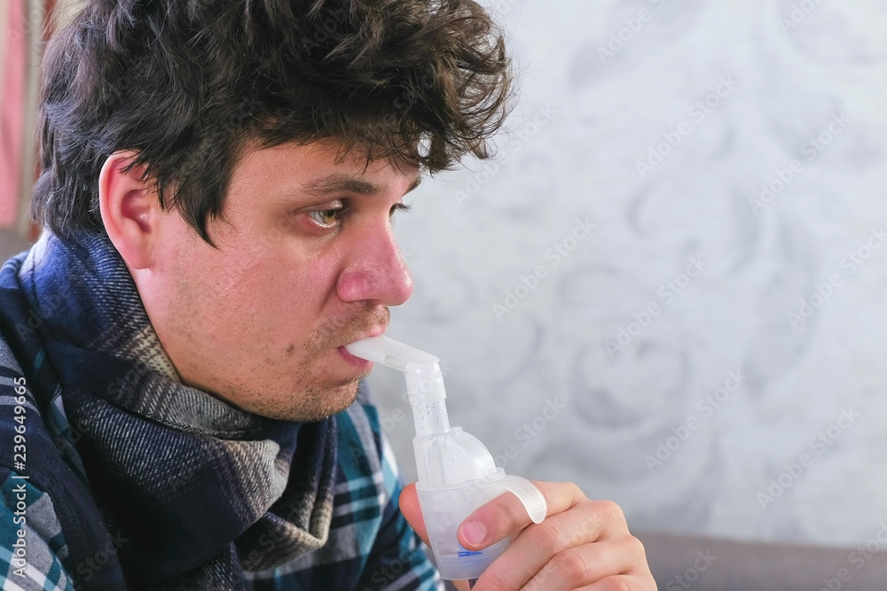 Use nebulizer and inhaler for the treatment. Sick man inhaling through inhaler nozzle for throat. Close-up face side view. Use nebulizer and inhaler for the treatment. Sick man inhaling through inhaler nozzle for throat. Close-up face side view.