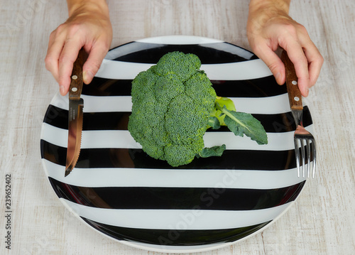 the concept of healthy. dietary food. green, raw broccoli lying on a plate, women's hands with devices. the view from the top. copy space. healthy diet. green cabbage close-up. HLS. photo