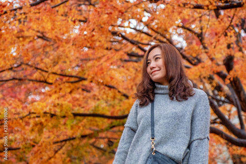 Portrait image of a beautiful asian woman standing among red and yellow colors tree leaves in autumn