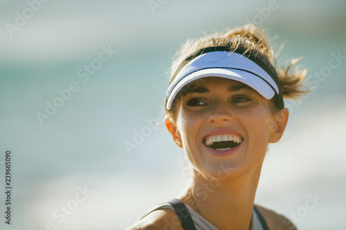 smiling fit sports woman on seacoast in evening