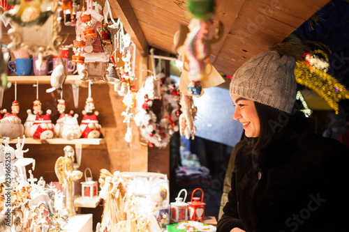 Happy young woman choosing Christmas decoration at market