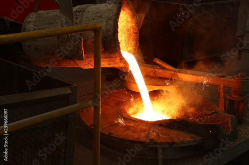 Molten iron pour from ladle into melting furnace ; industry foundry metallurgy engineering background