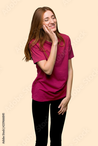 Young redhead girl with toothache on isolated yellow background