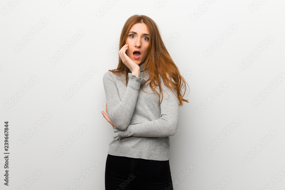 Redhead girl over white wall surprised and shocked while looking right Redhead girl over white wall surprised and shocked while looking right