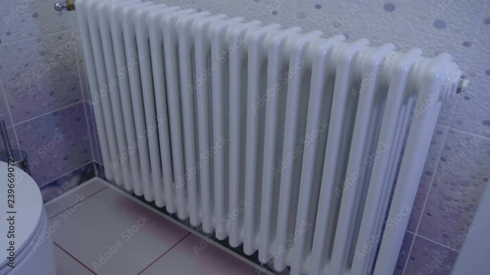 Beautiful white radiator (battery, heated towel rail) in the bathroom, lined with ceramic tiles. Shot in motion Beautiful white radiator (battery, heated towel rail) in the bathroom, lined with ceramic tiles. Shot in motion