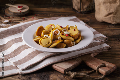 Pickled mushrooms in white bowl on wooden background countryhouse style salt pepper