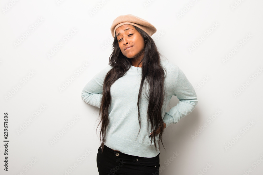 Young afro american woman on white wall suffering from backache for having made an effort Young afro american woman on white wall suffering from backache for having made an effort
