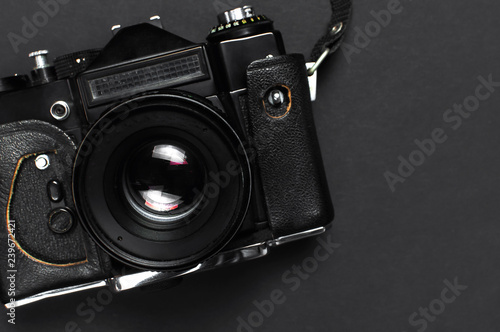 Old retro vintage camera in a leather case on black background top view flat lay with copy space. Concept for the photographer, old photographic equipment, minimalistic style selective focus