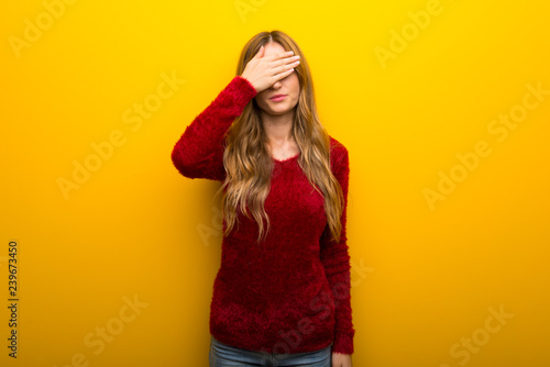 Young girl on vibrant yellow background covering eyes by hands. Do not want to see something
