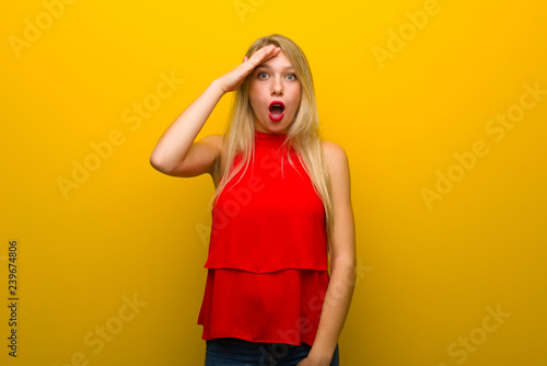 Young girl with red dress over yellow wall has just realized something and has intending the solution