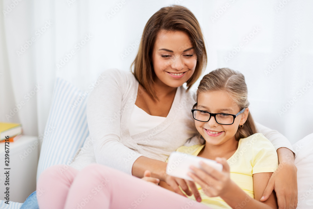 people, family and technology concept - happy mother and daughter with smartphone at home people, family and technology concept - happy mother and daughter with smartphone at home