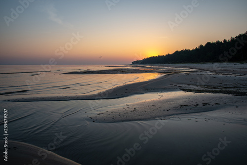 sandy sea beach with rocks and low tide in overcast day