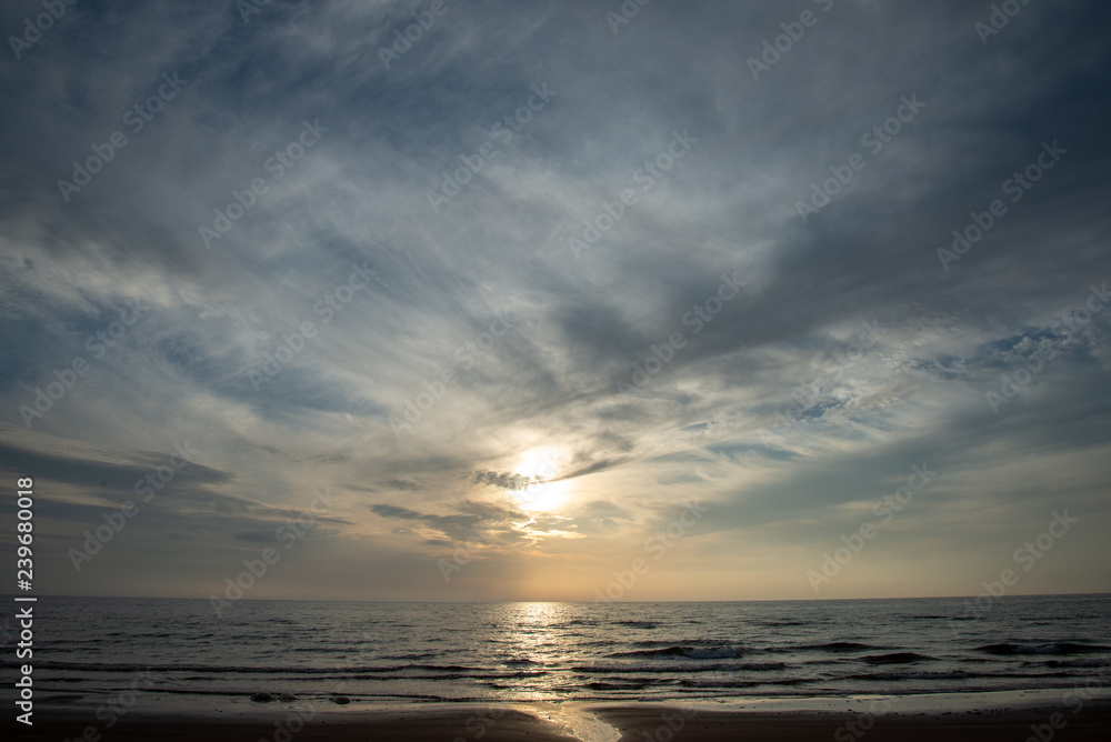 Naklejka premium dramatic high contrast clouds in sunset over seaside beach