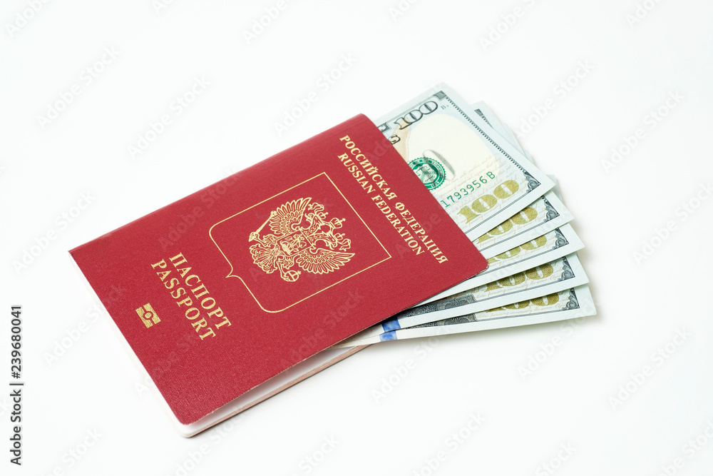 Biometric travel passport of the Russian Federation with dollars isolated on white background. Five bills for a hundred dollars. The concept of tourism. The concept of investment. Closeup. Biometric travel passport of the Russian Federation with dollars isolated on white background. Five bills for a hundred dollars. The concept of tourism. The concept of investment. Closeup.