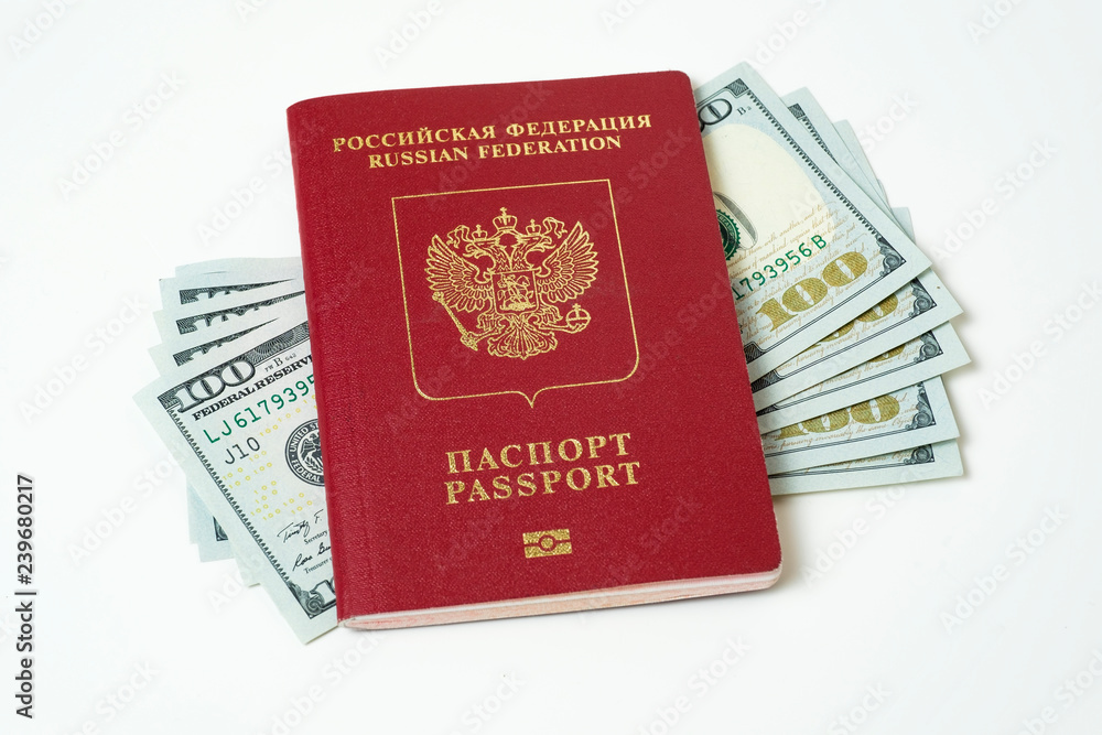 Biometric travel passport of the Russian Federation with dollars isolated on white background. Five bills for a hundred dollars. The concept of tourism. The concept of investment. Closeup. Biometric travel passport of the Russian Federation with dollars isolated on white background. Five bills for a hundred dollars. The concept of tourism. The concept of investment. Closeup.