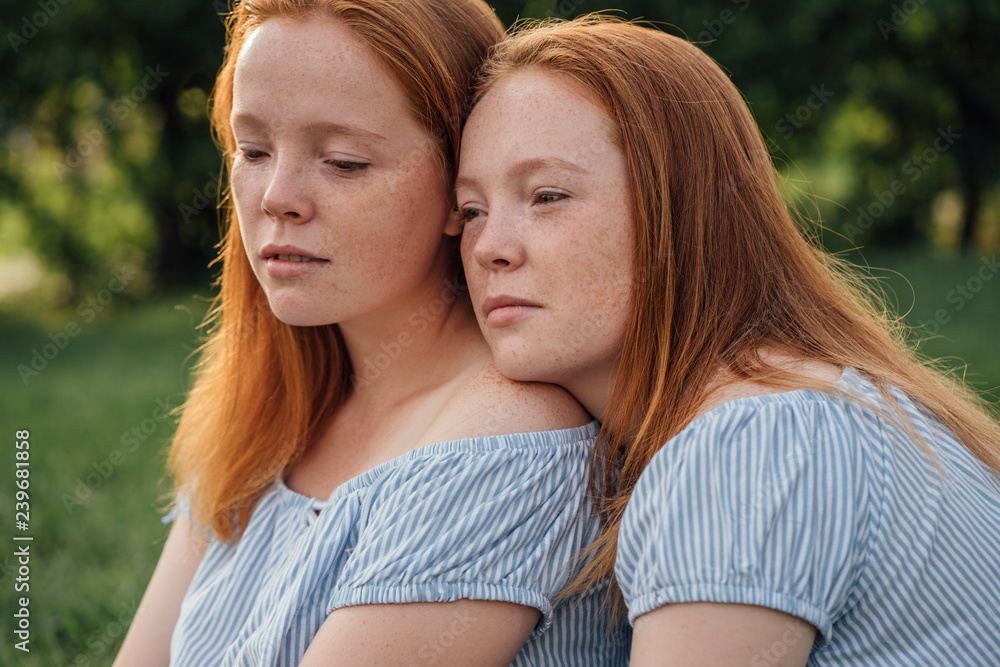 Thoughtful redhead twins sitting outdoors Thoughtful redhead twins sitting outdoors