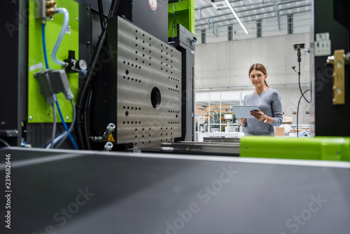 Businesswoman in high tech company controlling manufacturing machines, using digital tablet photo